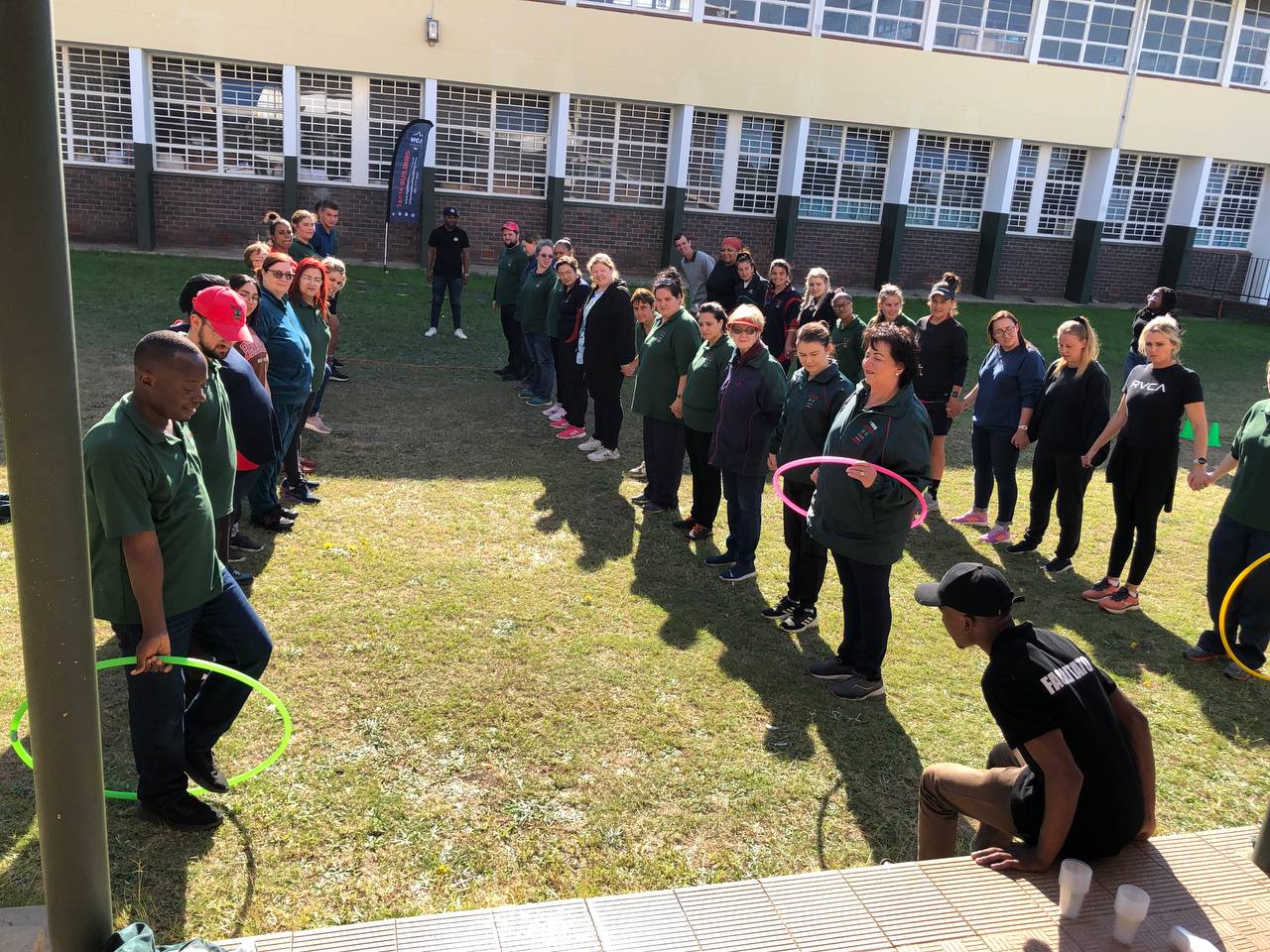 Workplace colleagues completing an MGA hoop activity on a school field